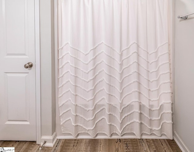 bathroom with wood finished floors, a shower with curtain, and baseboards