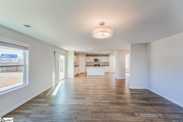 unfurnished living room with light wood-style floors, baseboards, and visible vents