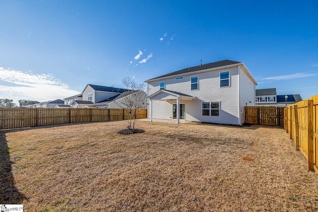 back of property with a fenced backyard and a lawn