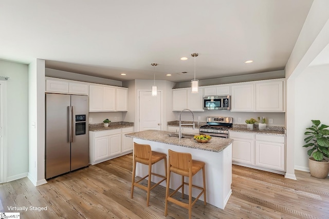 kitchen with light wood-style floors, white cabinets, recessed lighting, appliances with stainless steel finishes, and a sink