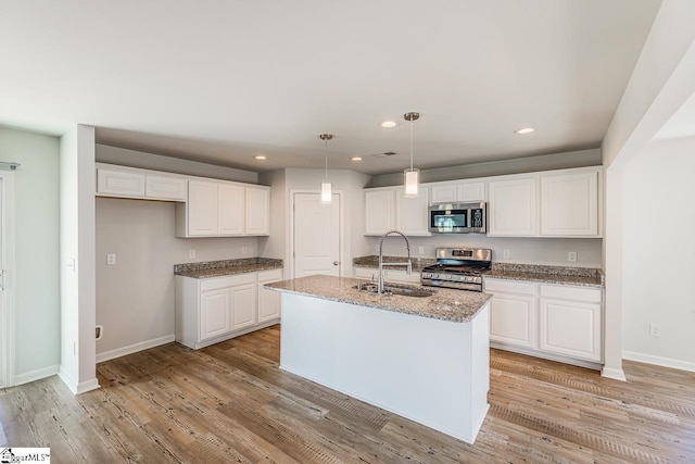 kitchen featuring light wood-type flooring, recessed lighting, white cabinets, appliances with stainless steel finishes, and a sink