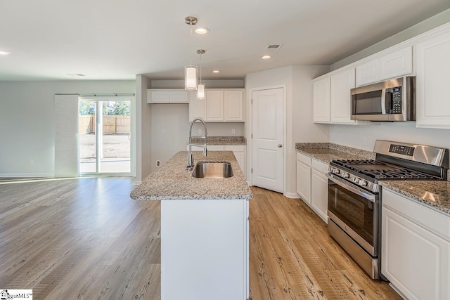 kitchen featuring light wood-type flooring, appliances with stainless steel finishes, an island with sink, and a sink