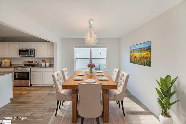 dining room featuring light wood-style flooring, an inviting chandelier, and baseboards