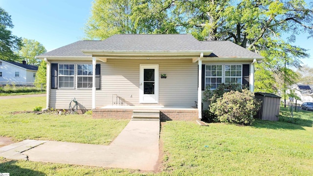 bungalow with a porch, an outdoor structure, a shed, and a front lawn