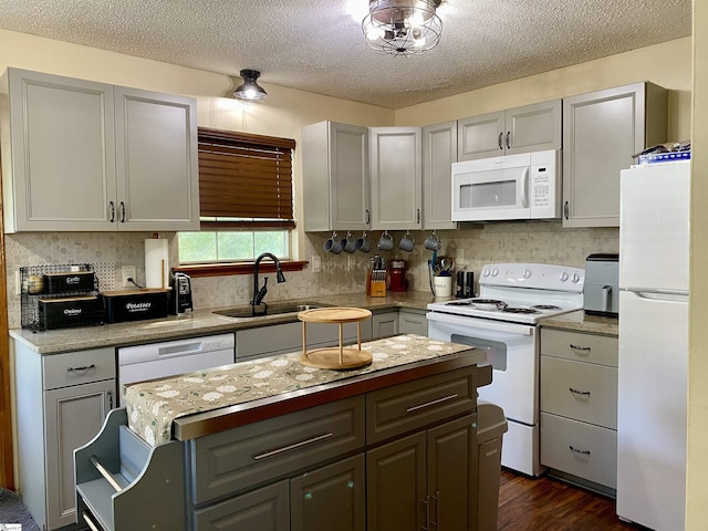kitchen with a sink, white appliances, a textured ceiling, a center island, and gray cabinetry