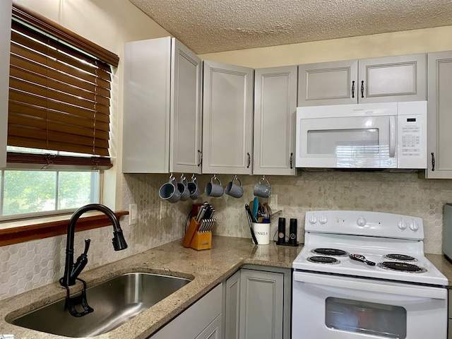 kitchen with white appliances, gray cabinets, a textured ceiling, tasteful backsplash, and a sink