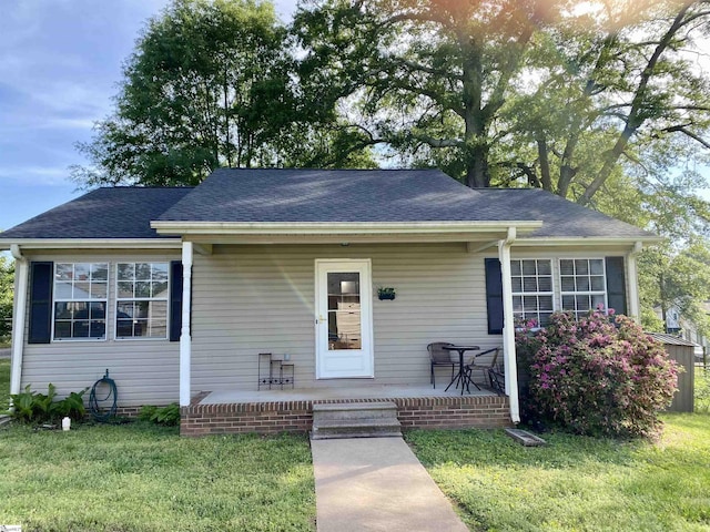 bungalow-style home with a porch, a shingled roof, and a front lawn
