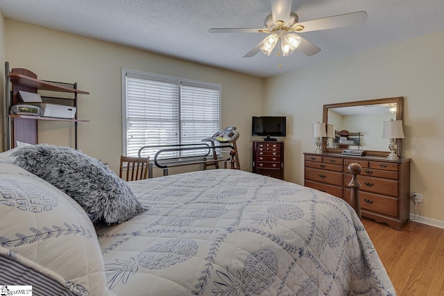 bedroom with ceiling fan, a textured ceiling, baseboards, and wood finished floors
