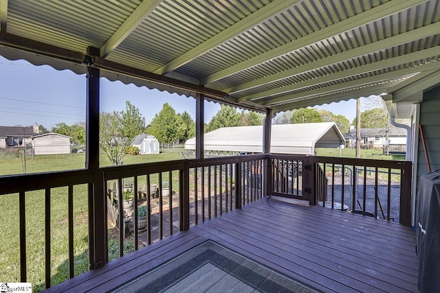 wooden terrace with an outbuilding, a shed, and a lawn