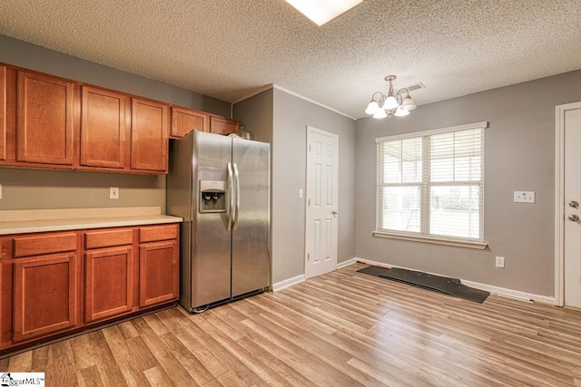kitchen featuring light wood finished floors, a notable chandelier, brown cabinetry, and stainless steel fridge