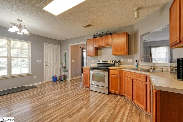 kitchen featuring a notable chandelier, a sink, light countertops, electric stove, and light wood finished floors