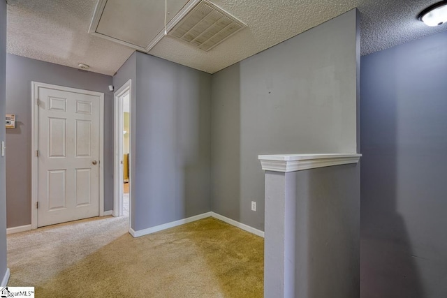 carpeted entrance foyer featuring visible vents, baseboards, and a textured ceiling