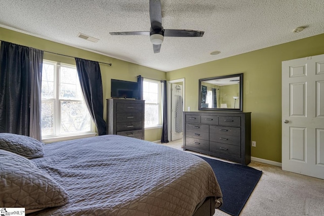 bedroom featuring baseboards, a textured ceiling, visible vents, ceiling fan, and light colored carpet