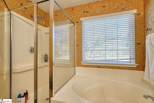 bathroom with a bath, a shower stall, and a textured ceiling