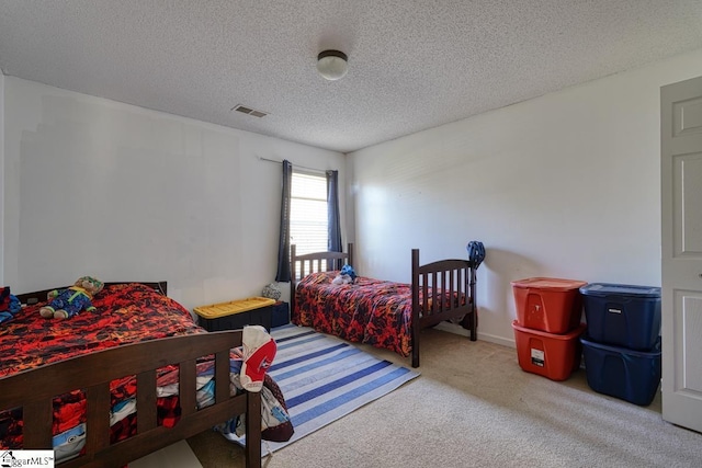 carpeted bedroom featuring a textured ceiling and visible vents