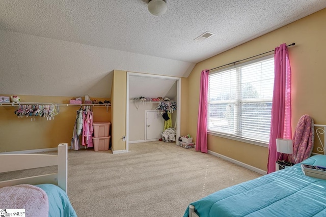carpeted bedroom with visible vents, a textured ceiling, baseboards, and lofted ceiling