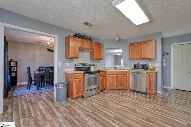 kitchen featuring light wood-style flooring, light countertops, visible vents, stainless steel appliances, and a sink