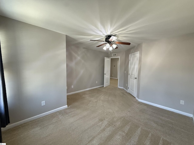 spare room with carpet flooring, a ceiling fan, baseboards, and visible vents