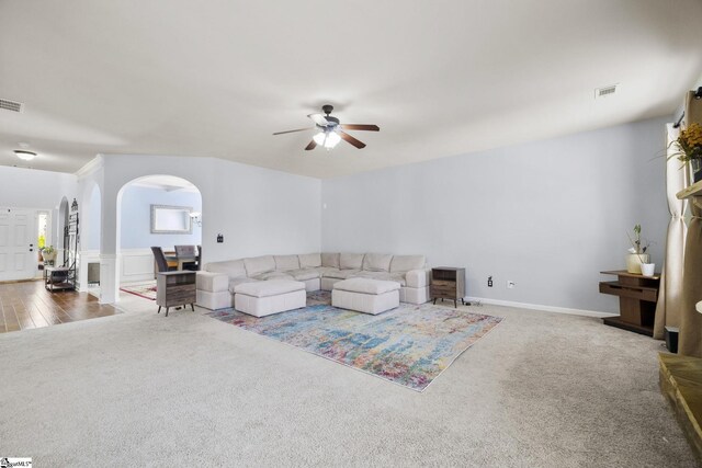 living room with arched walkways, ceiling fan, visible vents, and carpet floors