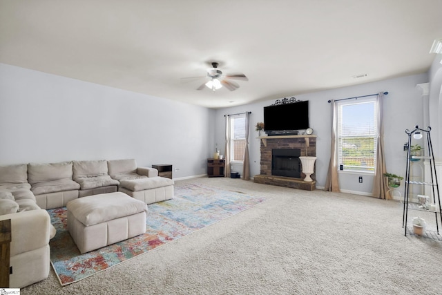 living area featuring a healthy amount of sunlight, a fireplace, a ceiling fan, and carpet floors