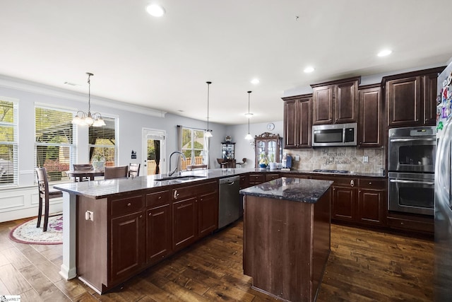 kitchen with appliances with stainless steel finishes, a sink, dark wood-style floors, and a kitchen island