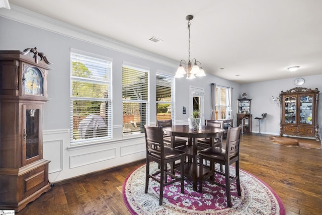 dining room with ornamental molding, a notable chandelier, visible vents, and dark wood-style floors