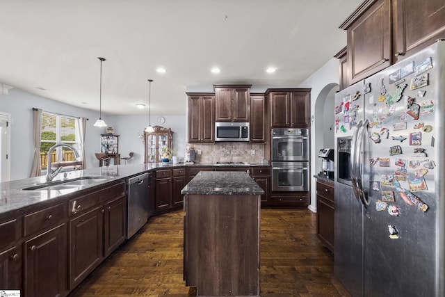 kitchen featuring dark stone countertops, appliances with stainless steel finishes, a sink, and dark wood-style floors
