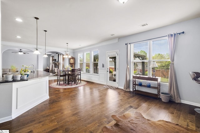 interior space with ceiling fan with notable chandelier, ornamental molding, visible vents, recessed lighting, and dark wood-style flooring