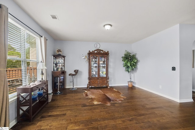 interior space with arched walkways, wood finished floors, baseboards, and visible vents