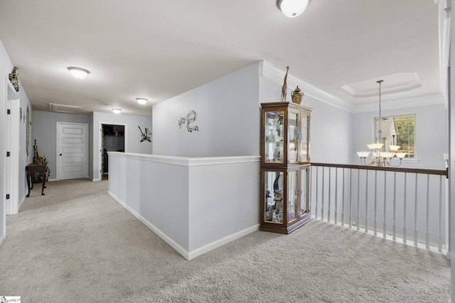 hall with carpet floors, an upstairs landing, attic access, and a raised ceiling