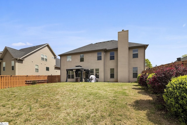 back of house featuring a chimney, a gazebo, fence, and a lawn