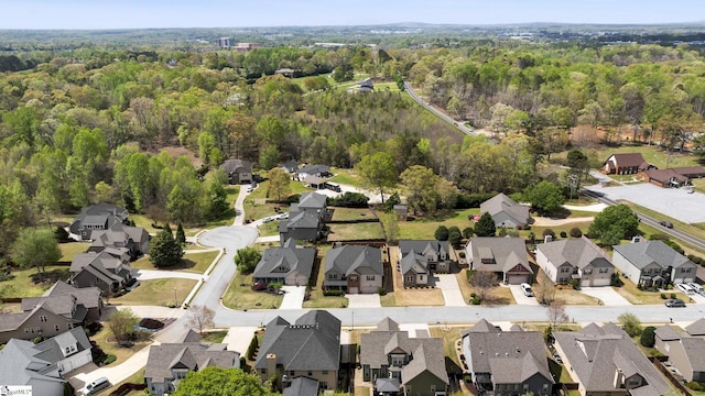 drone / aerial view featuring a wooded view and a residential view