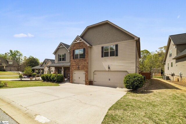 craftsman-style home with cooling unit, a front yard, brick siding, a garage, and concrete driveway