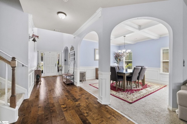 foyer entrance featuring coffered ceiling, arched walkways, beam ceiling, and stairs