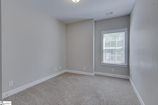 empty room with baseboards, visible vents, and light colored carpet