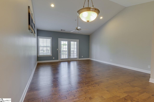 spare room featuring ceiling fan, dark wood-type flooring, visible vents, baseboards, and lofted ceiling