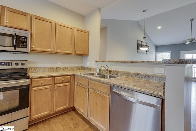 kitchen featuring lofted ceiling, a sink, appliances with stainless steel finishes, ceiling fan, and light wood finished floors