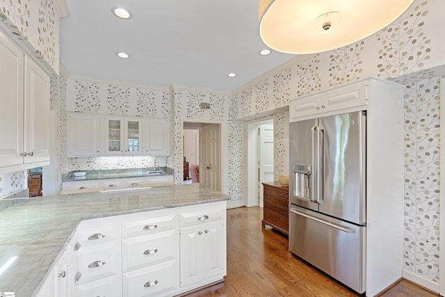 kitchen featuring crown molding, high end fridge, white cabinets, and wallpapered walls