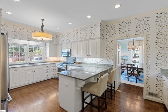 kitchen featuring stainless steel appliances, a peninsula, crown molding, and dark wood finished floors