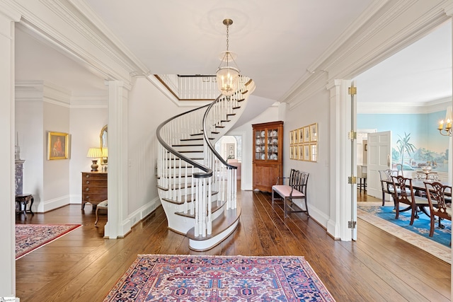 entryway featuring crown molding, an inviting chandelier, wood-type flooring, and stairs
