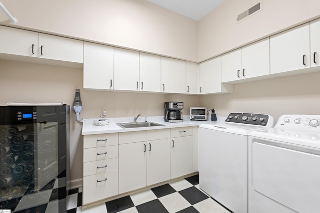 laundry area with laundry area, light floors, independent washer and dryer, visible vents, and a sink