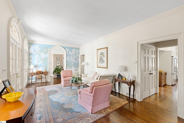 living area featuring hardwood / wood-style floors, wallpapered walls, crown molding, and baseboards