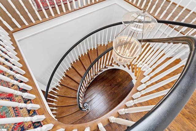 stairs featuring a chandelier and wood finished floors