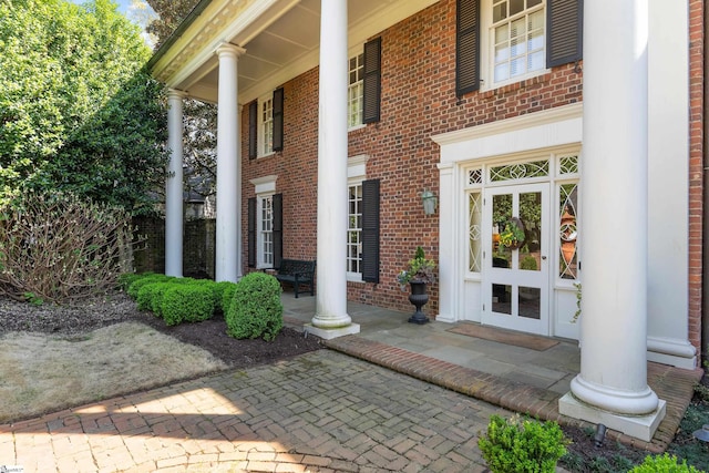 doorway to property featuring brick siding and covered porch