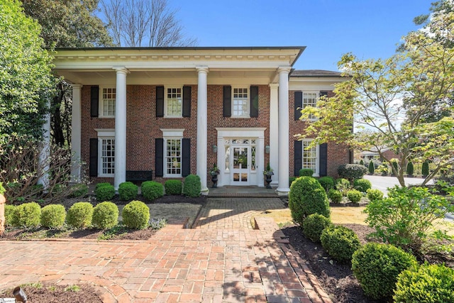 neoclassical home featuring brick siding and french doors