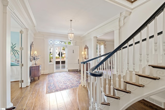 entrance foyer featuring stairs, light wood finished floors, crown molding, and a decorative wall