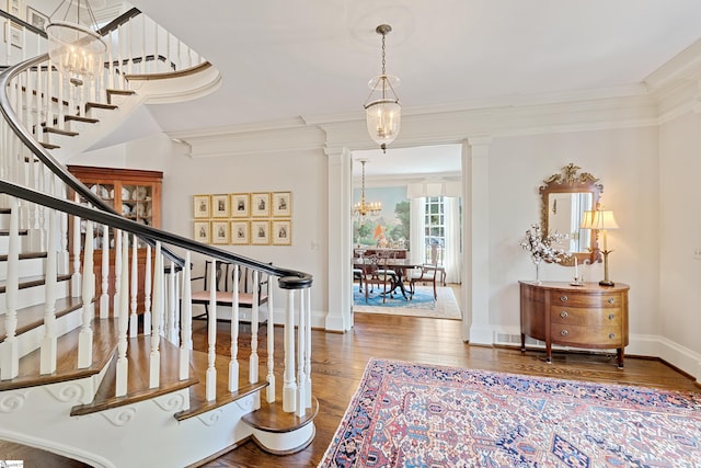 foyer entrance with stairway, an inviting chandelier, crown molding, and wood finished floors