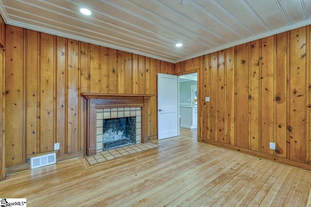 506 Parkview Dr, Spartanburg, SC 29302 - unfurnished living room featuring wood walls, a tiled fireplace, visible vents, and hardwood / wood-style flooring