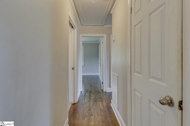 hallway with visible vents, baseboards, crown molding, attic access, and dark wood-type flooring