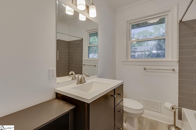 bathroom featuring vanity, ornamental molding, visible vents, toilet, and wood finished floors